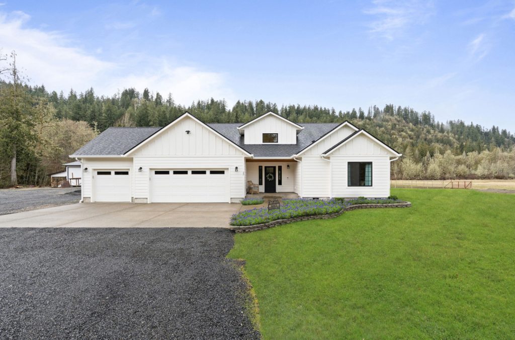 Real Estate Photography Services capturing a white home nestled amidst a grassy field, complete with a garage.