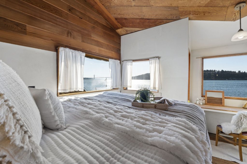 A bedroom with a bed and a breathtaking view of the water captured beautifully by Real Estate Photography Services.